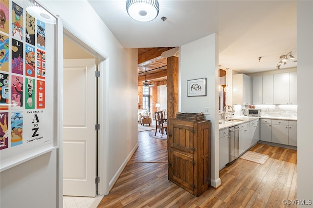 kitchen featuring tasteful backsplash, dishwasher, sink, and light hardwood / wood-style floors