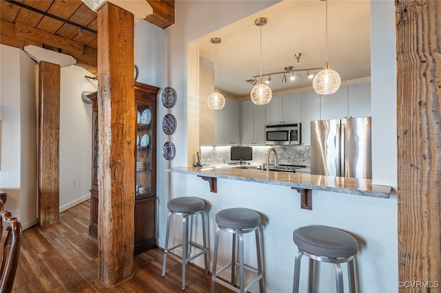 kitchen featuring a breakfast bar, decorative light fixtures, decorative backsplash, kitchen peninsula, and stainless steel appliances