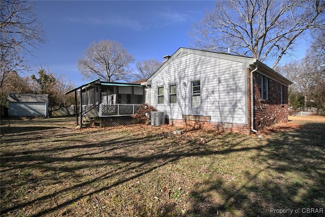 rear view of house with a sunroom, central AC unit, and a lawn