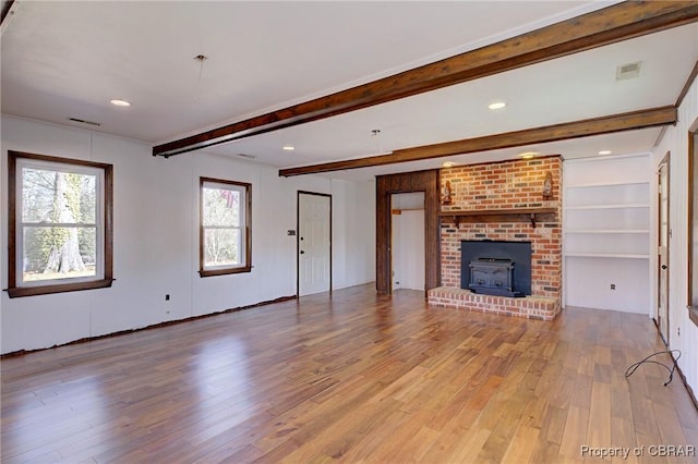 unfurnished living room featuring hardwood / wood-style flooring, a wood stove, and beamed ceiling