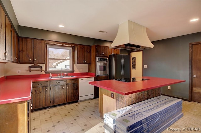 kitchen featuring island exhaust hood, stainless steel appliances, sink, and dark brown cabinetry