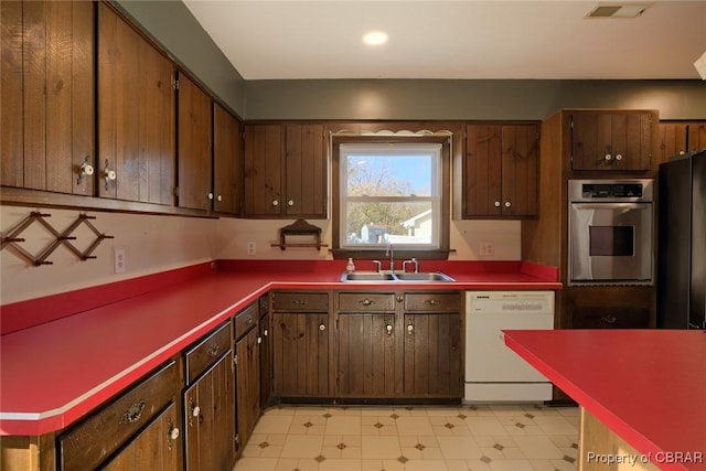 kitchen with black fridge, sink, oven, and white dishwasher