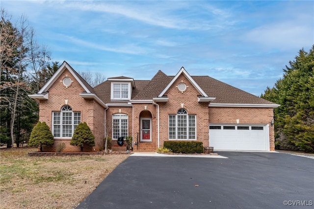 traditional home with driveway, a shingled roof, a garage, and brick siding