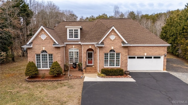 traditional-style home featuring a garage, driveway, roof with shingles, and brick siding