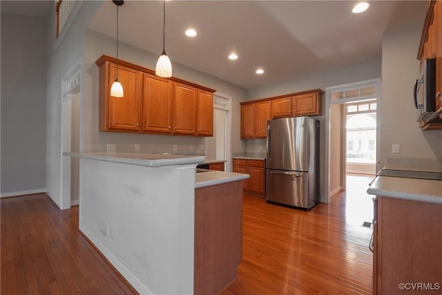 kitchen with appliances with stainless steel finishes, light hardwood / wood-style flooring, and decorative light fixtures