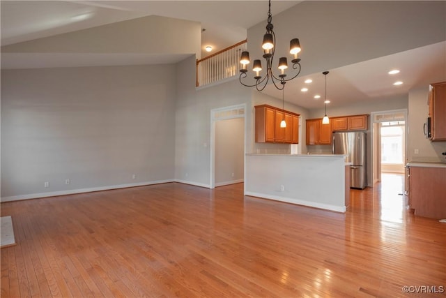 unfurnished living room featuring an inviting chandelier, light hardwood / wood-style floors, and a high ceiling