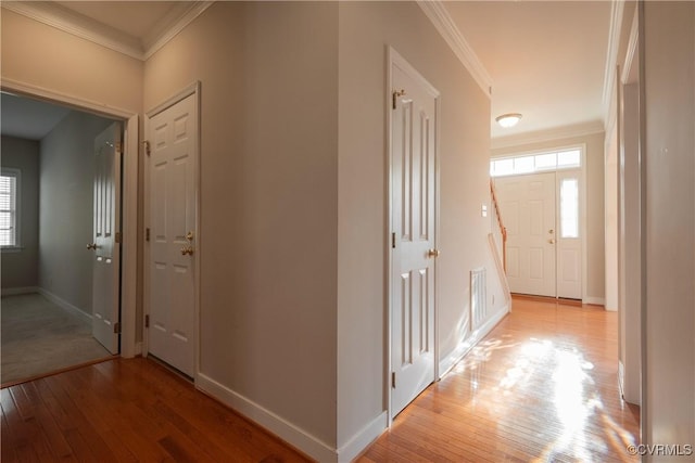 corridor with ornamental molding and light hardwood / wood-style floors