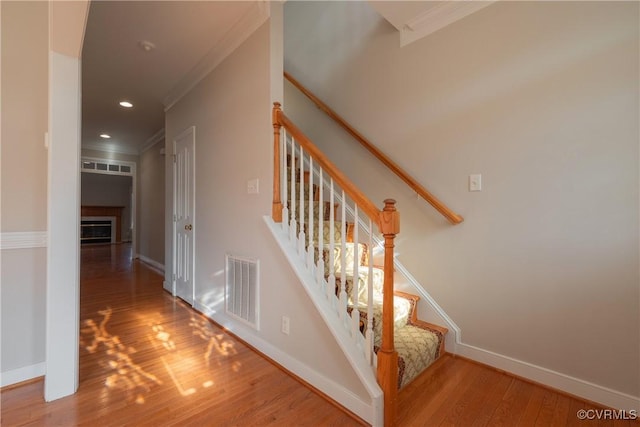 stairs featuring wood-type flooring and ornamental molding