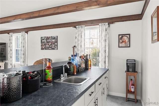 kitchen with beamed ceiling, sink, and white cabinets