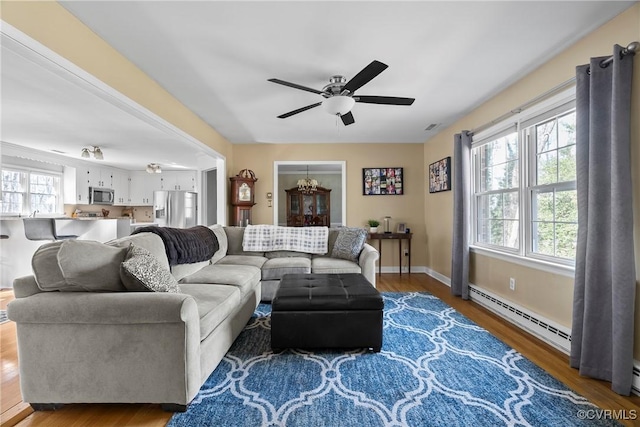 living room with hardwood / wood-style flooring, a baseboard radiator, and ceiling fan with notable chandelier