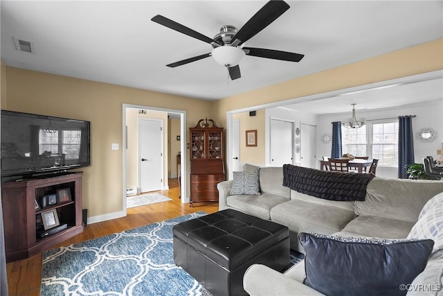 living room with hardwood / wood-style flooring and ceiling fan with notable chandelier