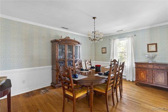 dining space with crown molding, a chandelier, and light wood-type flooring