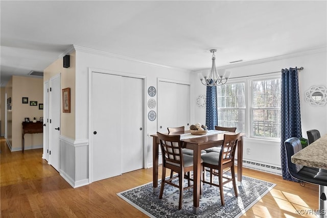 dining area featuring ornamental molding, a notable chandelier, light hardwood / wood-style floors, and baseboard heating