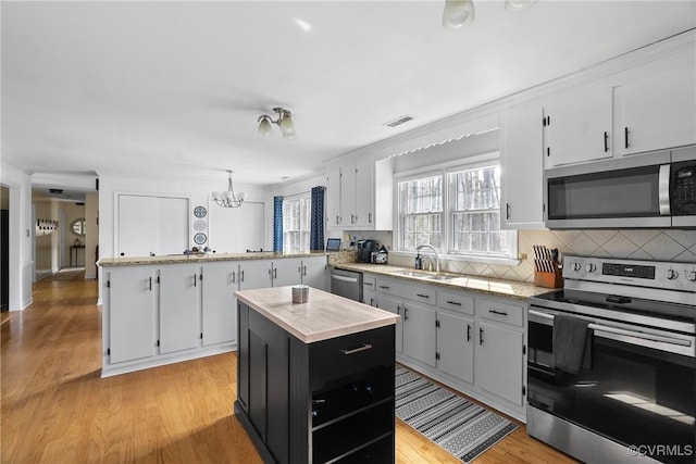 kitchen featuring white cabinetry, stainless steel appliances, a center island, and sink