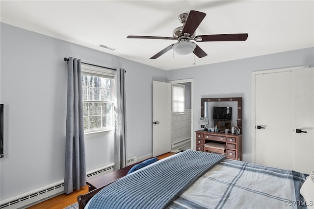 bedroom featuring hardwood / wood-style flooring, ceiling fan, and baseboard heating