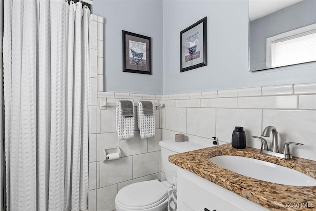 bathroom featuring vanity, toilet, and tile walls