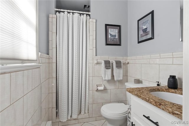 bathroom featuring tile patterned floors, vanity, toilet, and tile walls