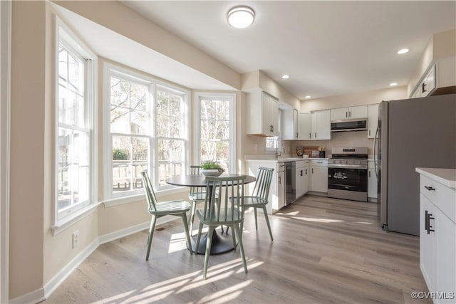 kitchen featuring white cabinetry, appliances with stainless steel finishes, extractor fan, and plenty of natural light