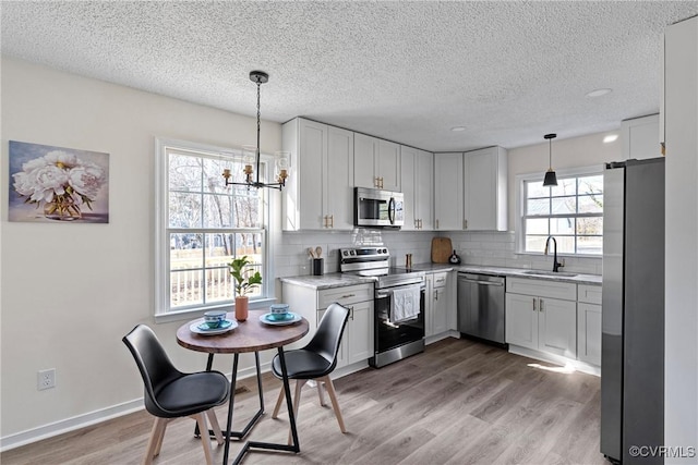 kitchen featuring white cabinetry, appliances with stainless steel finishes, backsplash, and decorative light fixtures