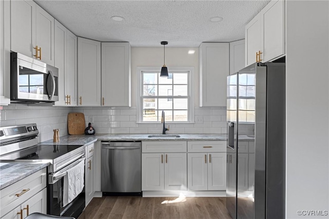 kitchen with sink, light stone counters, appliances with stainless steel finishes, dark hardwood / wood-style floors, and white cabinets