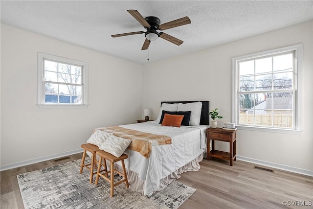 bedroom featuring a textured ceiling, multiple windows, and light hardwood / wood-style flooring