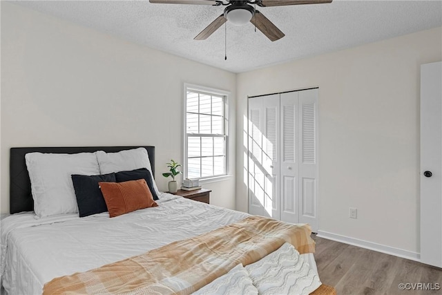 bedroom featuring ceiling fan, a textured ceiling, light hardwood / wood-style floors, and a closet