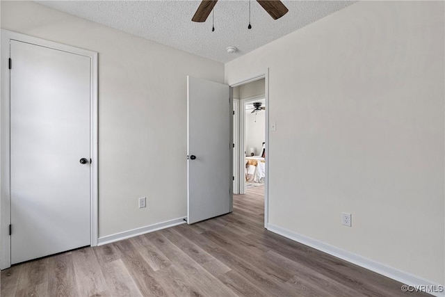 unfurnished bedroom featuring ceiling fan, a textured ceiling, and light hardwood / wood-style flooring