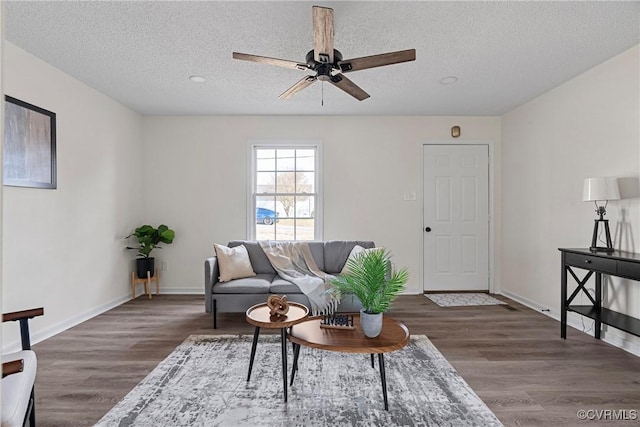 living room with ceiling fan, dark wood-type flooring, and a textured ceiling