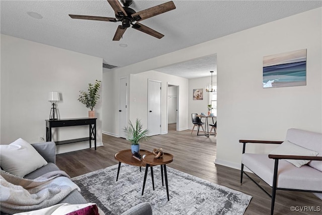 living room with dark hardwood / wood-style floors, ceiling fan with notable chandelier, and a textured ceiling