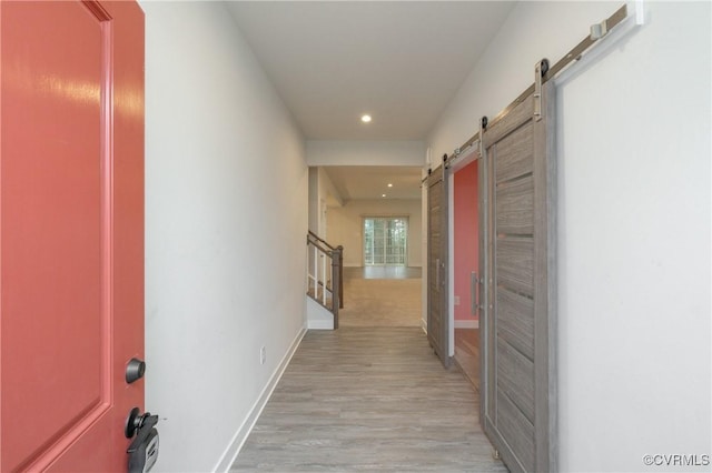 corridor with a barn door and light hardwood / wood-style flooring