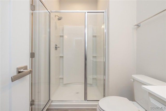 bathroom featuring vanity, toilet, and a shower with door