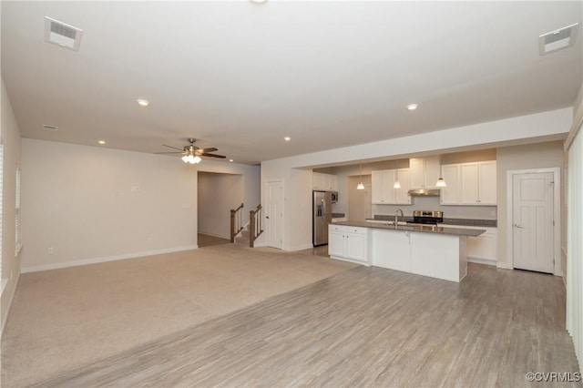 kitchen with appliances with stainless steel finishes, white cabinetry, a kitchen island with sink, ceiling fan, and light wood-type flooring