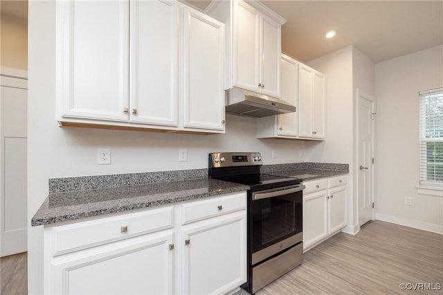 kitchen with electric stove, white cabinetry, light hardwood / wood-style flooring, and dark stone counters