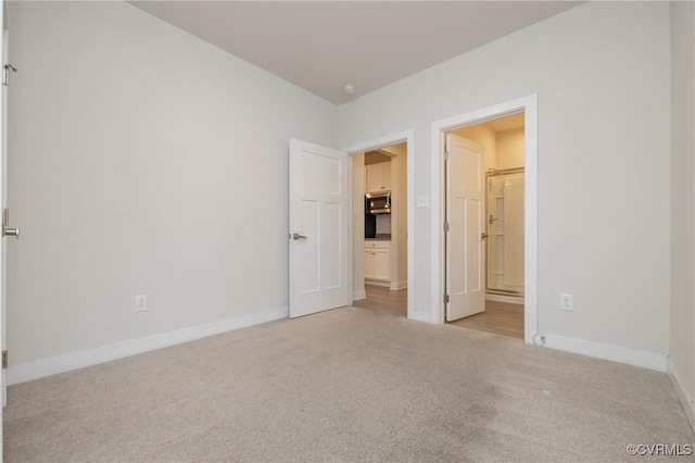 unfurnished bedroom featuring light carpet and connected bathroom