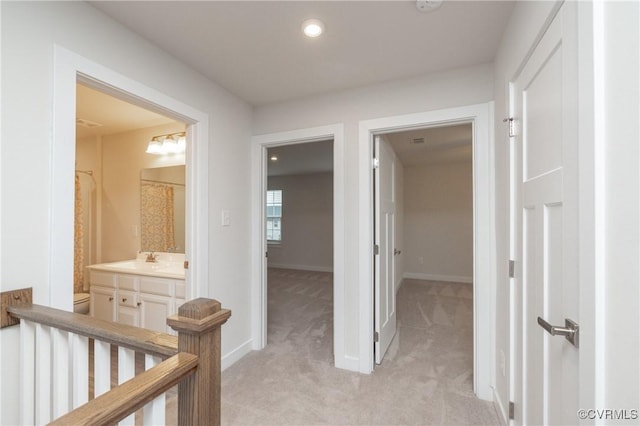 corridor featuring sink and light colored carpet