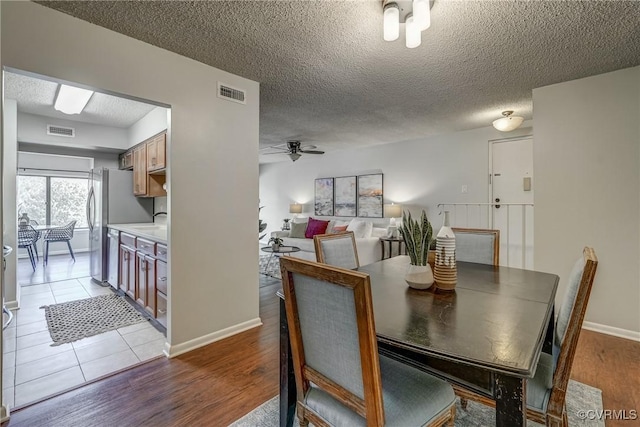 dining space featuring ceiling fan, wood-type flooring, sink, and a textured ceiling