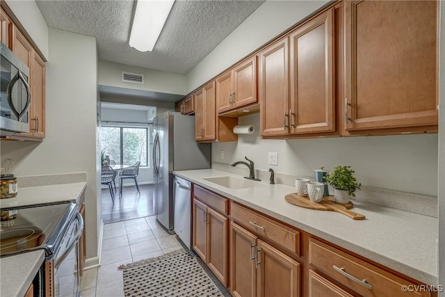 kitchen featuring sink, stainless steel appliances, a textured ceiling, and light tile patterned flooring