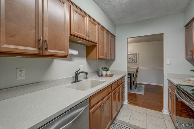 kitchen featuring stainless steel appliances, sink, light tile patterned floors, and a textured ceiling