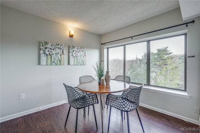 dining area with dark wood-type flooring and a textured ceiling