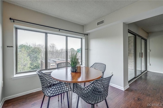 dining space with dark hardwood / wood-style floors and a textured ceiling