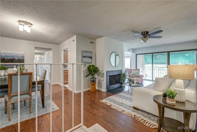 living room with hardwood / wood-style flooring, a textured ceiling, and ceiling fan