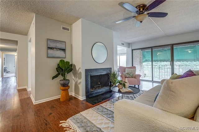 living room with ceiling fan, dark wood-type flooring, and a textured ceiling