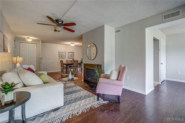 living room with ceiling fan, dark hardwood / wood-style floors, and a textured ceiling