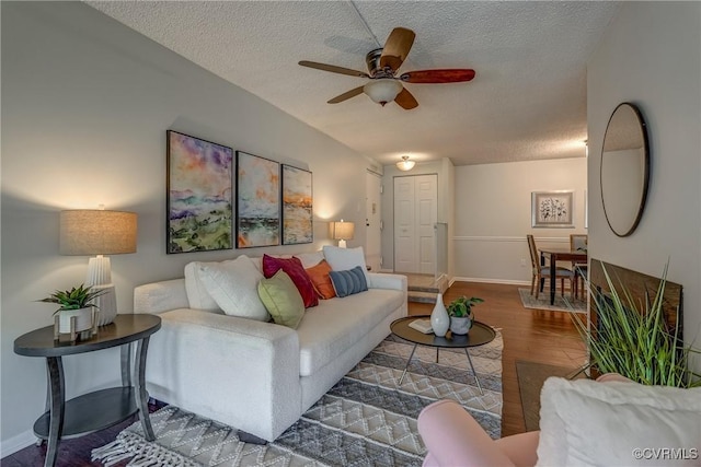 living room featuring ceiling fan, wood-type flooring, vaulted ceiling, and a textured ceiling