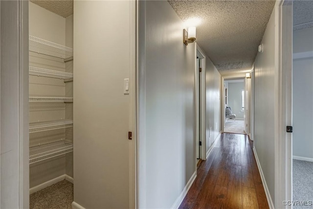 corridor with dark hardwood / wood-style floors and a textured ceiling