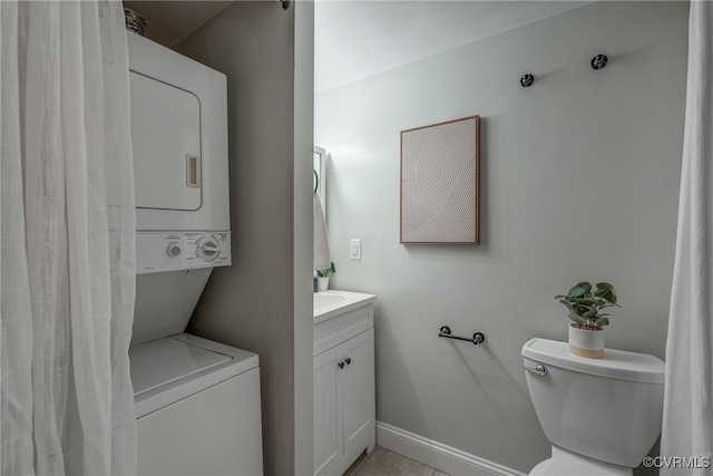 bathroom featuring stacked washer / dryer, toilet, and vanity