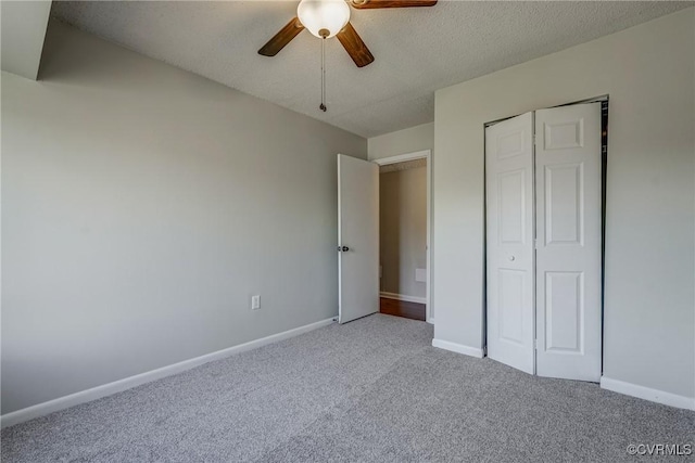 unfurnished bedroom with ceiling fan, carpet floors, a closet, and a textured ceiling