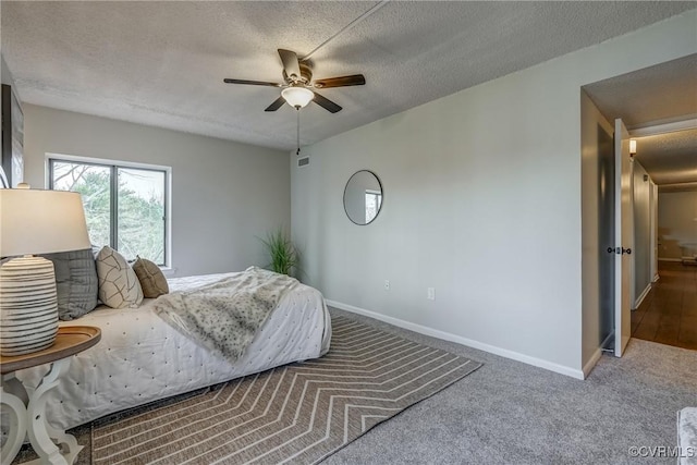 carpeted bedroom featuring ceiling fan and a textured ceiling