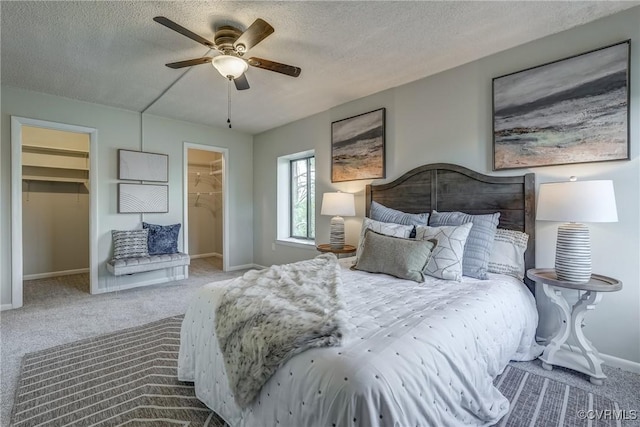 carpeted bedroom featuring ceiling fan, a spacious closet, a closet, and a textured ceiling