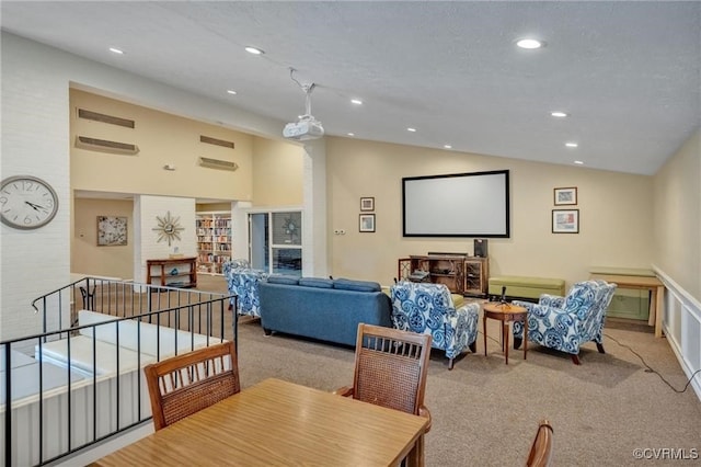 carpeted home theater room featuring vaulted ceiling and a textured ceiling